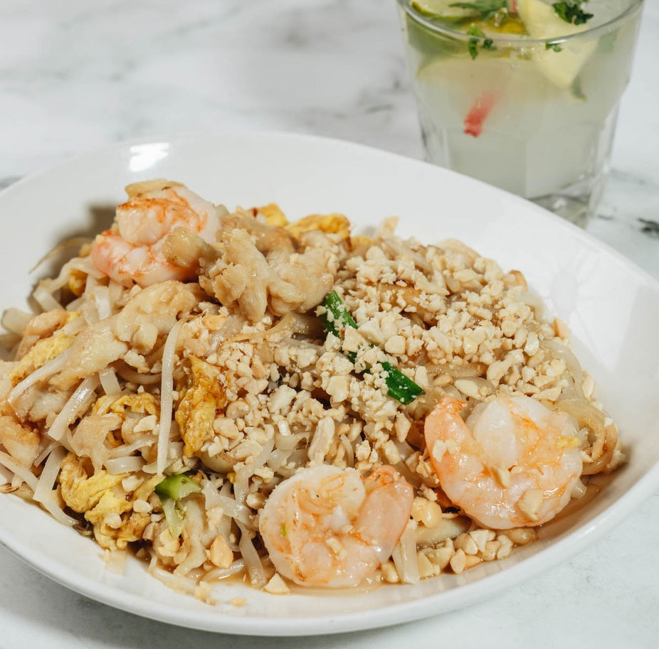 `Shrimp pad thai with crushed peanuts, egg, and bean sprouts in a white bowl`