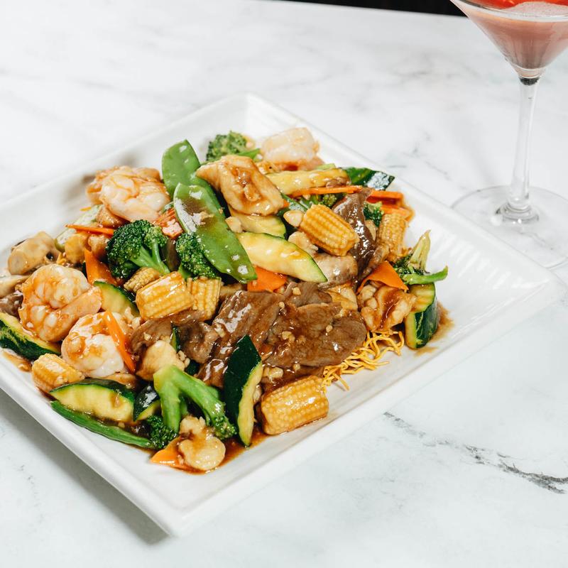 Beef and shrimp stir-fry with mixed vegetables on crispy noodles