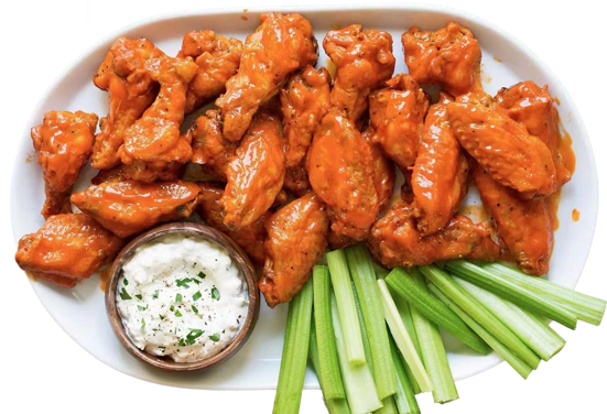 Buffalo chicken wings platter with celery sticks and blue cheese dip on white plate