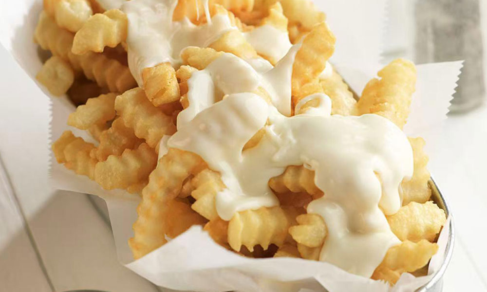 Crinkle-cut French fries covered in melted white cheese sauce