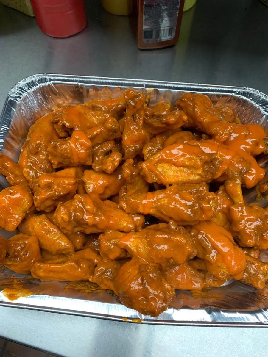 Spicy buffalo chicken wings in a foil tray at Wings & Seafood, a Seafood Restaurant in Ridgewood