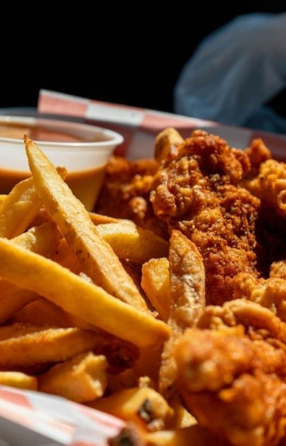 Crispy fried chicken tenders with golden fries and dipping sauce at Wing Star, a American fusion restaurant in Amsterdam