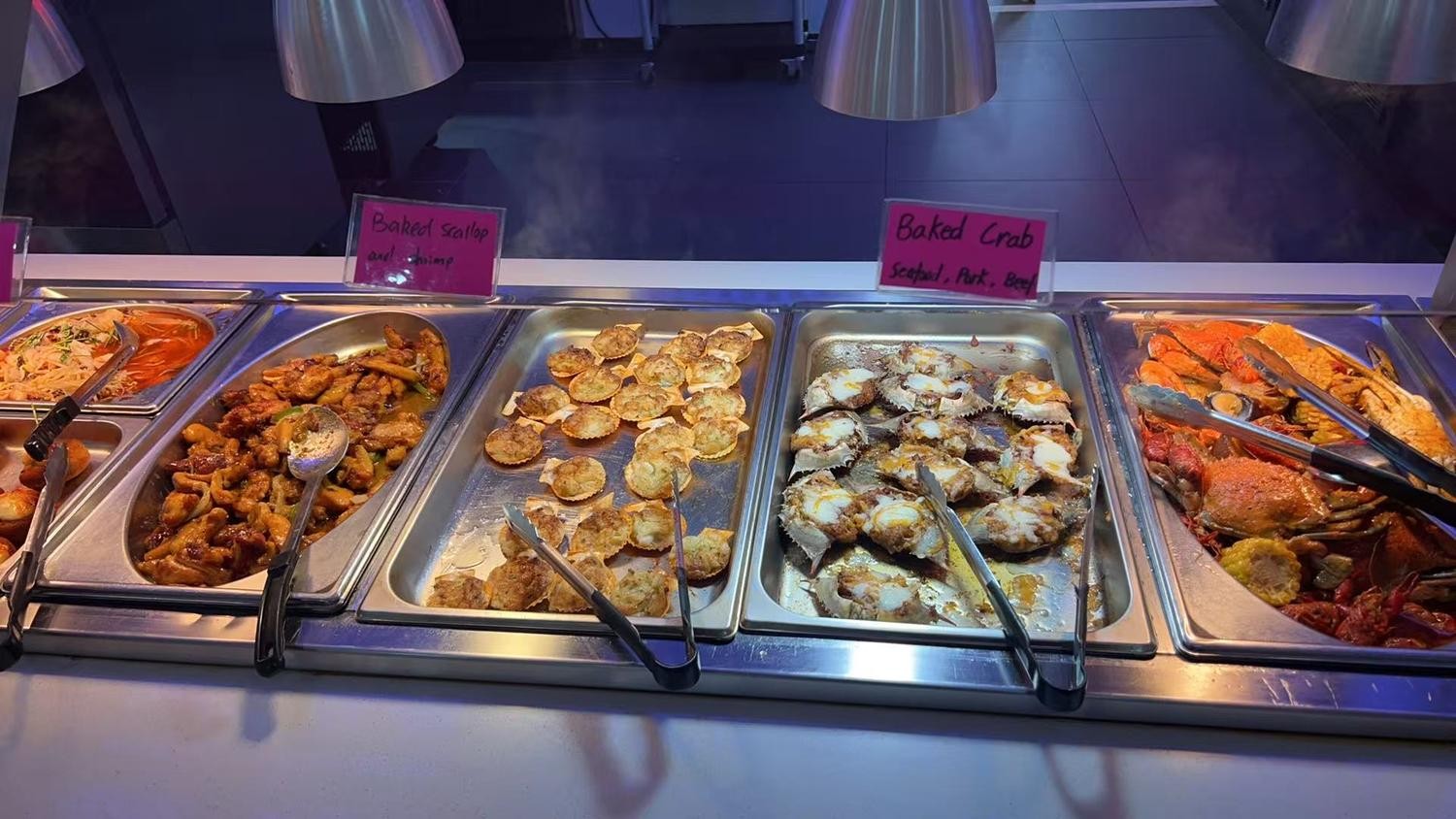 Metal trays with baked scallops, crab and cooked stir-fries at YC Seafood Hot Pot, a Hot Pot Restaurant in Virginia Beach