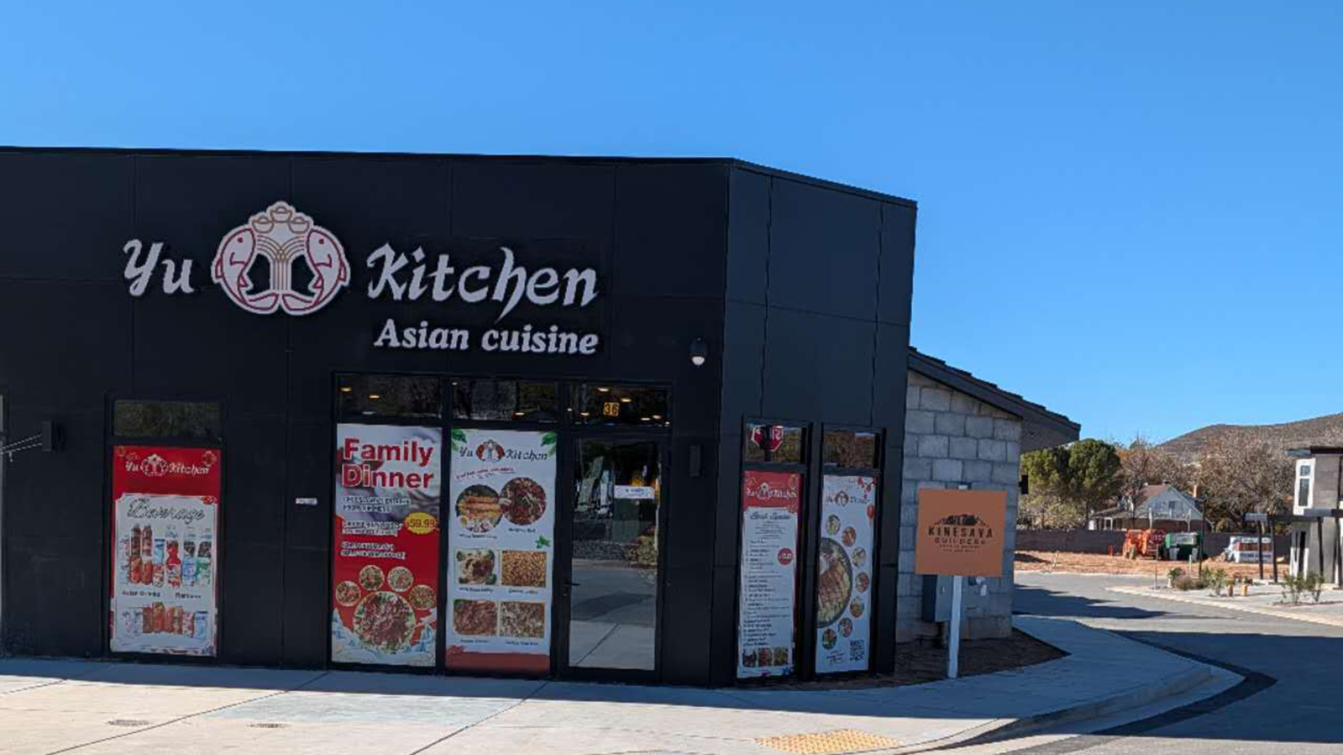 The exterior of Yu Kitchen, an Asian cuisine restaurant, featuring its logo with two fish and an "OPEN" sign in the window.