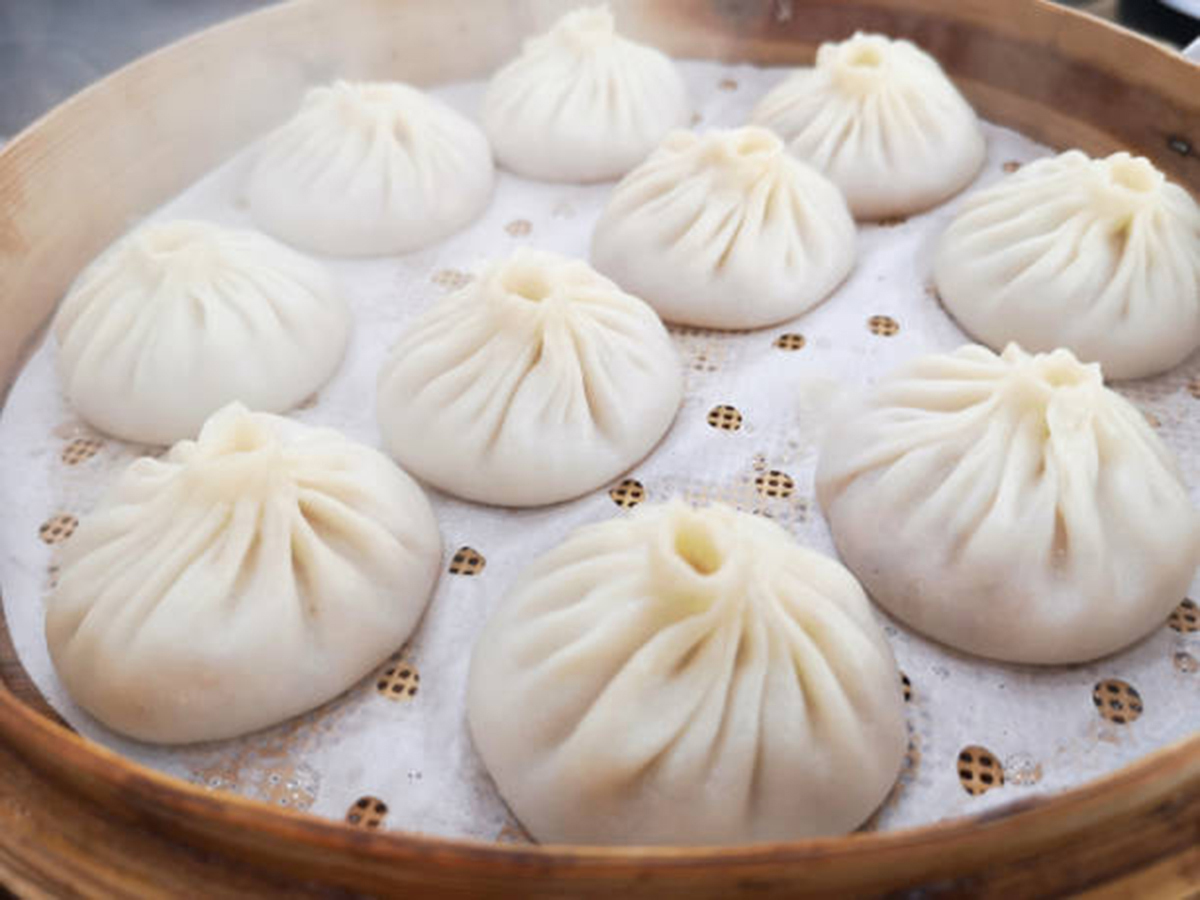 3 black buns, a bowl of fried rice, and a plate of dumplings