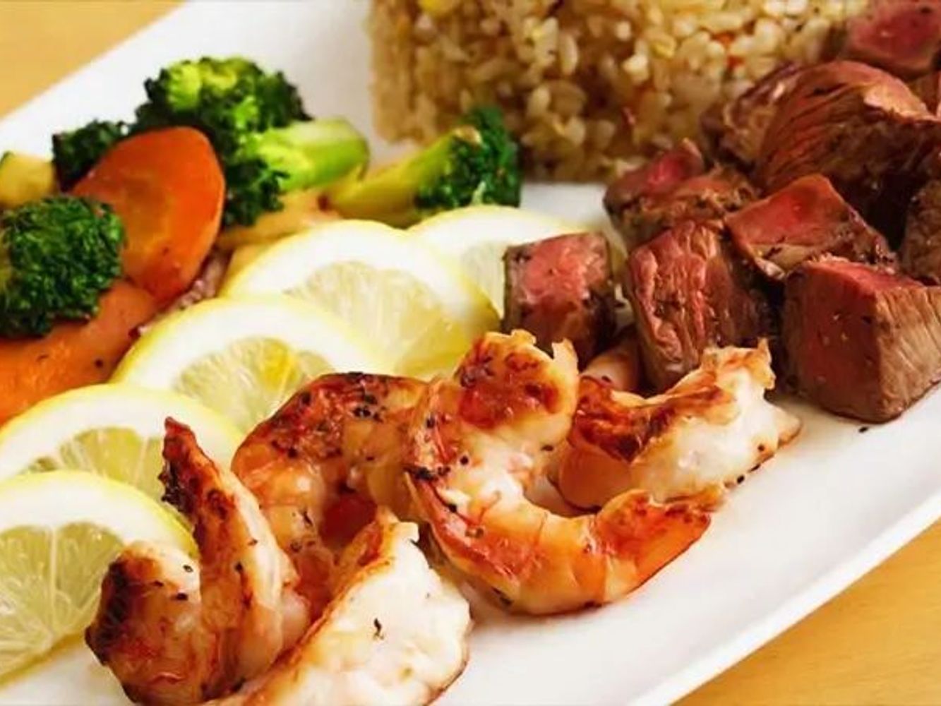 Grilled steak and shrimp platter with lemon, vegetables and fried rice