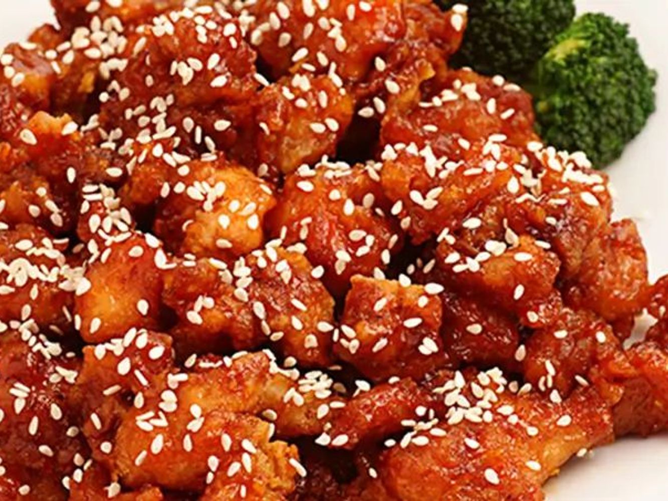 Sesame coated spicy chicken bites garnished with fresh broccoli