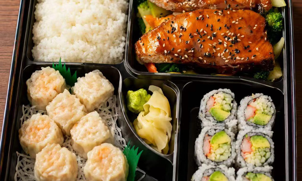 Bento box with teriyaki salmon, shumai dumplings, sushi rolls, and rice at Yu San, a Japanese Restaurant in East Stroudsburg