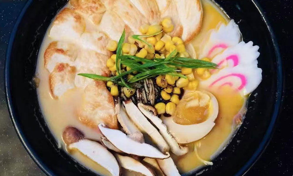 Creamy tonkotsu ramen with grilled chicken, corn, mushrooms, and narutomaki at Yu San, a Japanese Restaurant in East Stroudsburg