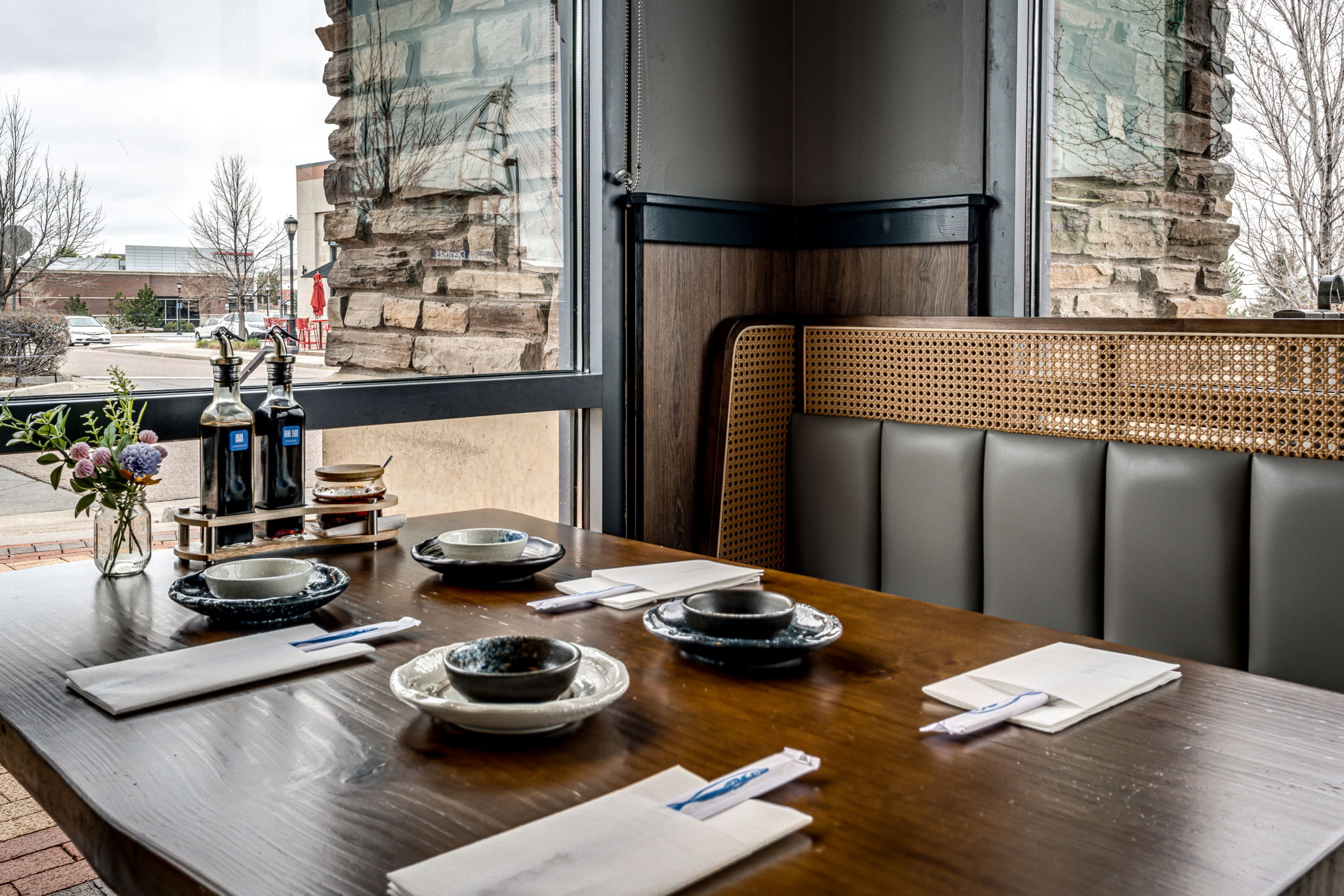 Yu's-Noodle-Shop-Chinese-restaurant-Lone-Tree Dining table by the window with plates, napkins, and condiments in a modern restaurant setting.