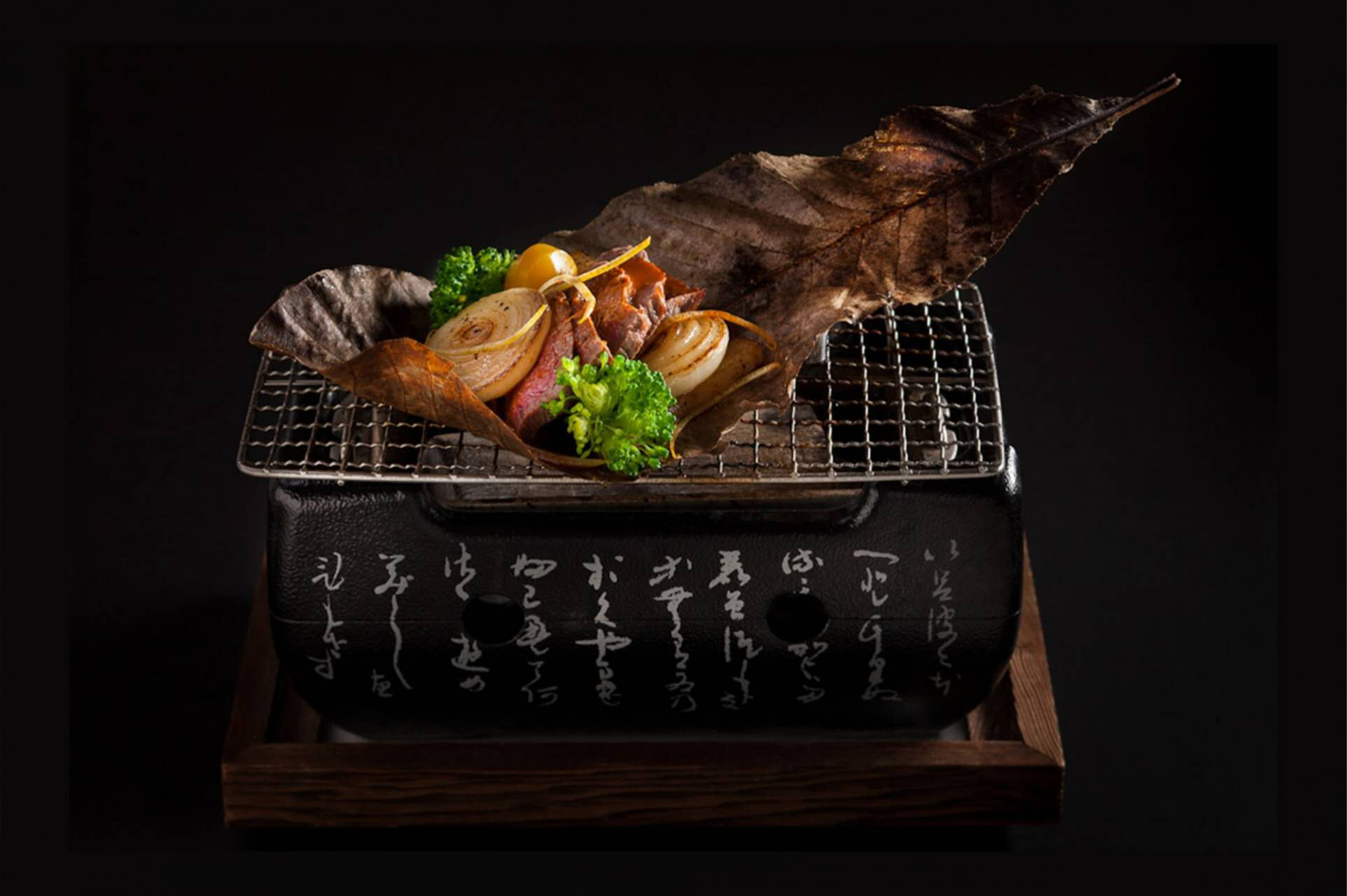 Grilled meat with onions and veggies on traditional Japanese grill.
