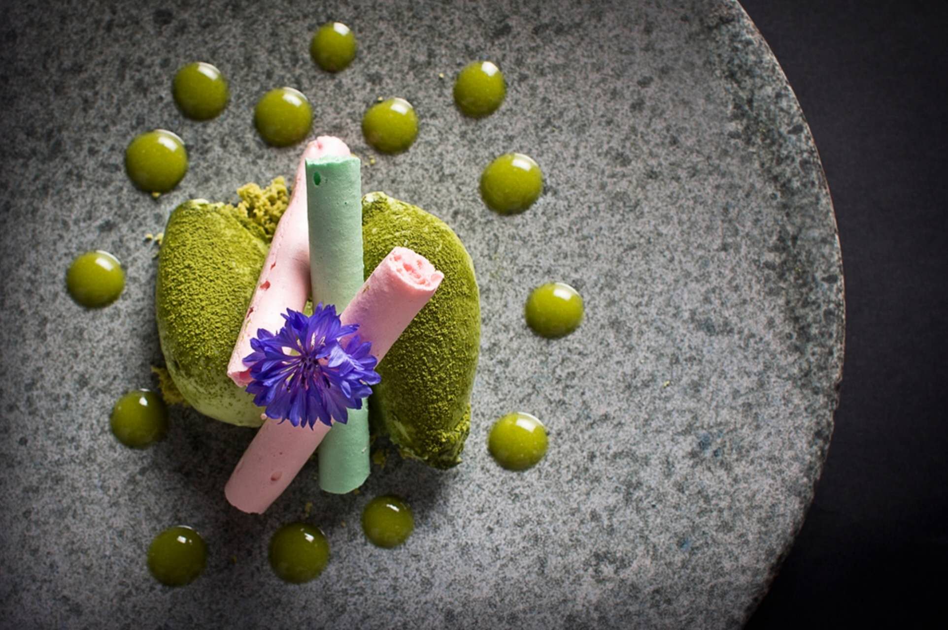 Matcha dessert with pink roll and purple flower decoration.