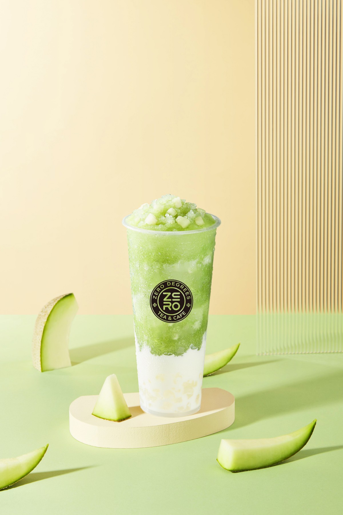 Zero-Degrees-Asian-inspired-Drink & Snack-Shop-Honeydew-Cream-topped-Specialty-Fruit-Tea-Bloomington A cup of honeydew cream - topped specialty fruit tea with honeydew pieces, placed on a light green background with honeydew slices around at Zero Degrees,a Asian-inspired Drink & Snack Shop in Bloomington