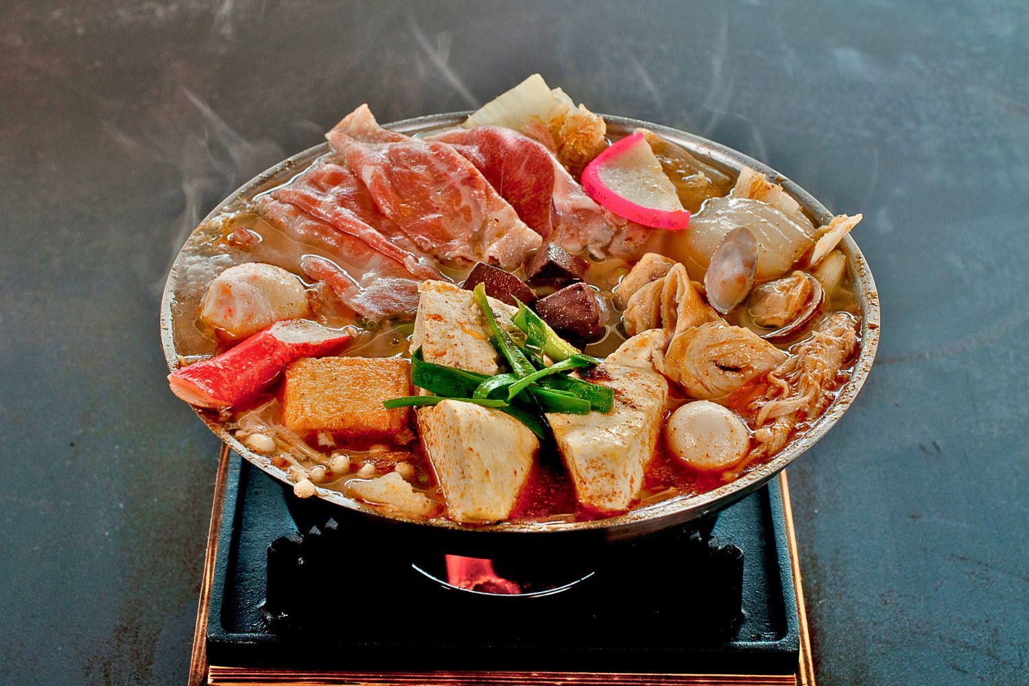 Spicy hot pot loaded with pork slices, clams, tofu, seafood balls and mixed veggies at ZhangLiang Malatang - Corona, a Chinese Restaurant in Corona