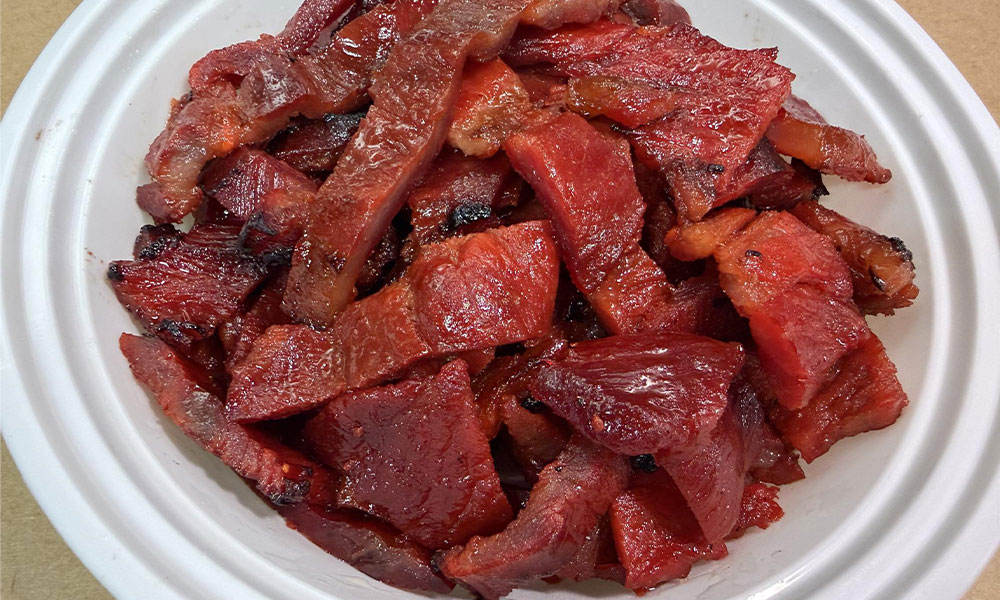 Sliced Chinese BBQ pork (char siu) in a white bowl, glazed and tender.