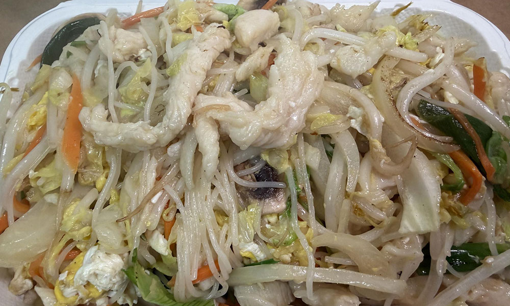Chicken chow mein with bean sprouts, cabbage, and egg in takeout container.