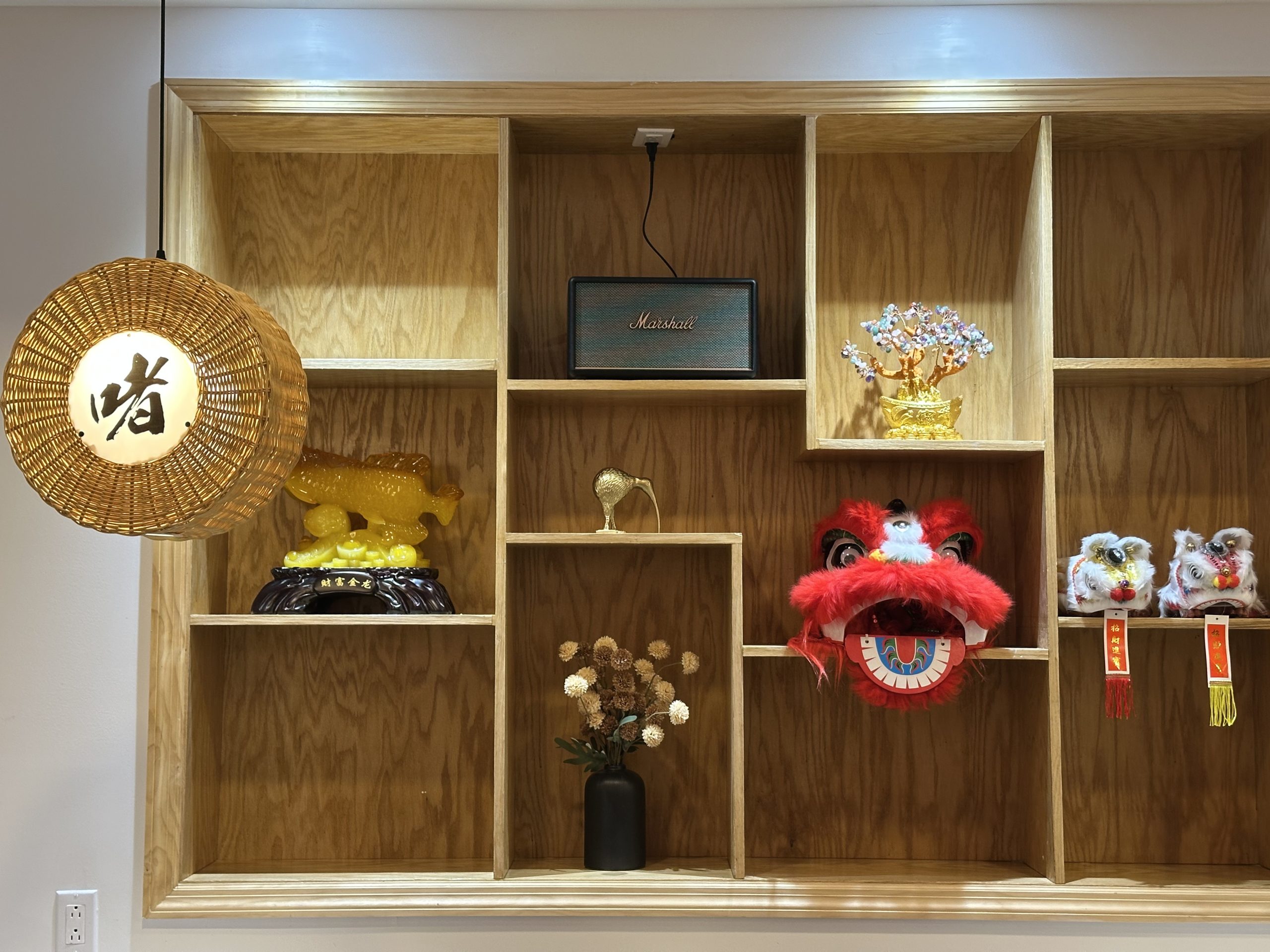Decorative shelf with lion dance masks and golden fish at Zhe Zhe Pot, a Chinese Restaurant in Brooklyn
