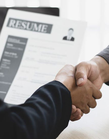 Two businesspeople shaking hands over a printed resume document on a light office table surface at Zhangliang Malatang, a Sichuan Malatang Spot in Los Angeles