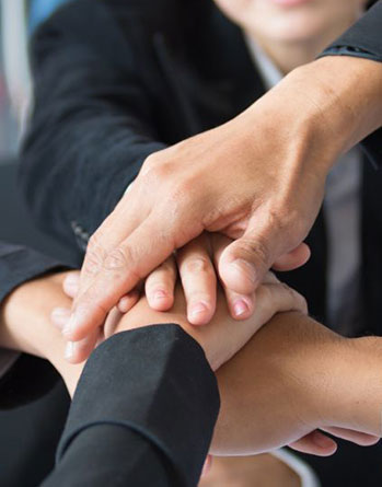 Close-up shot of multiple business team hands stacked together to show unity and cooperation indoors at Zhangliang Malatang, a Sichuan Malatang Spot in Los Angeles